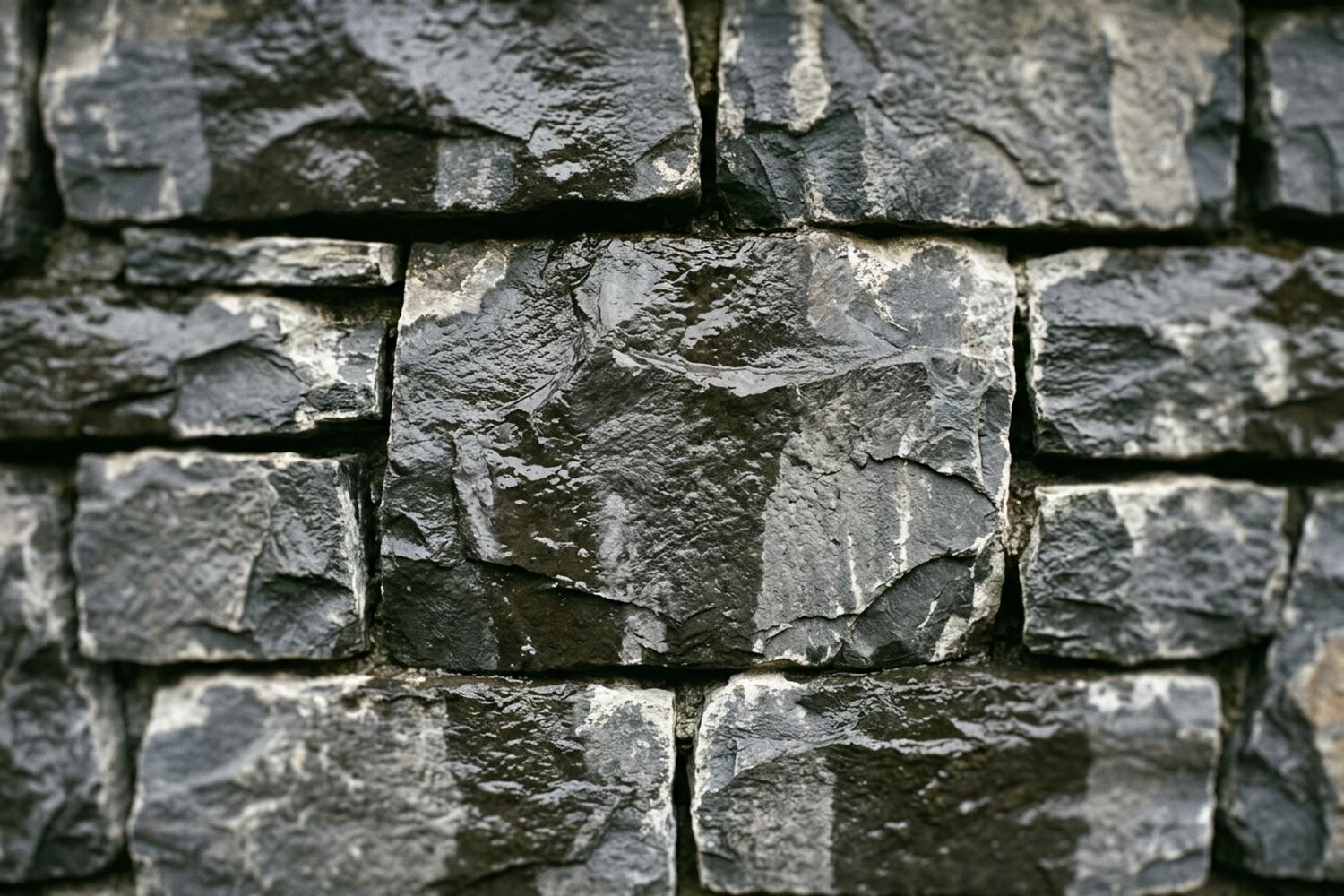 A wall of wet dark slate drying in patches, so the surface reads as two tones.