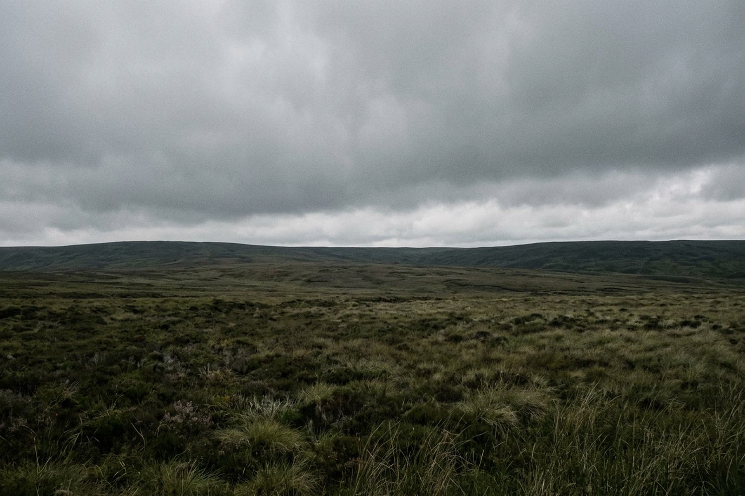 Unbroken overcast pressing down over a flat empty moor in low even light.