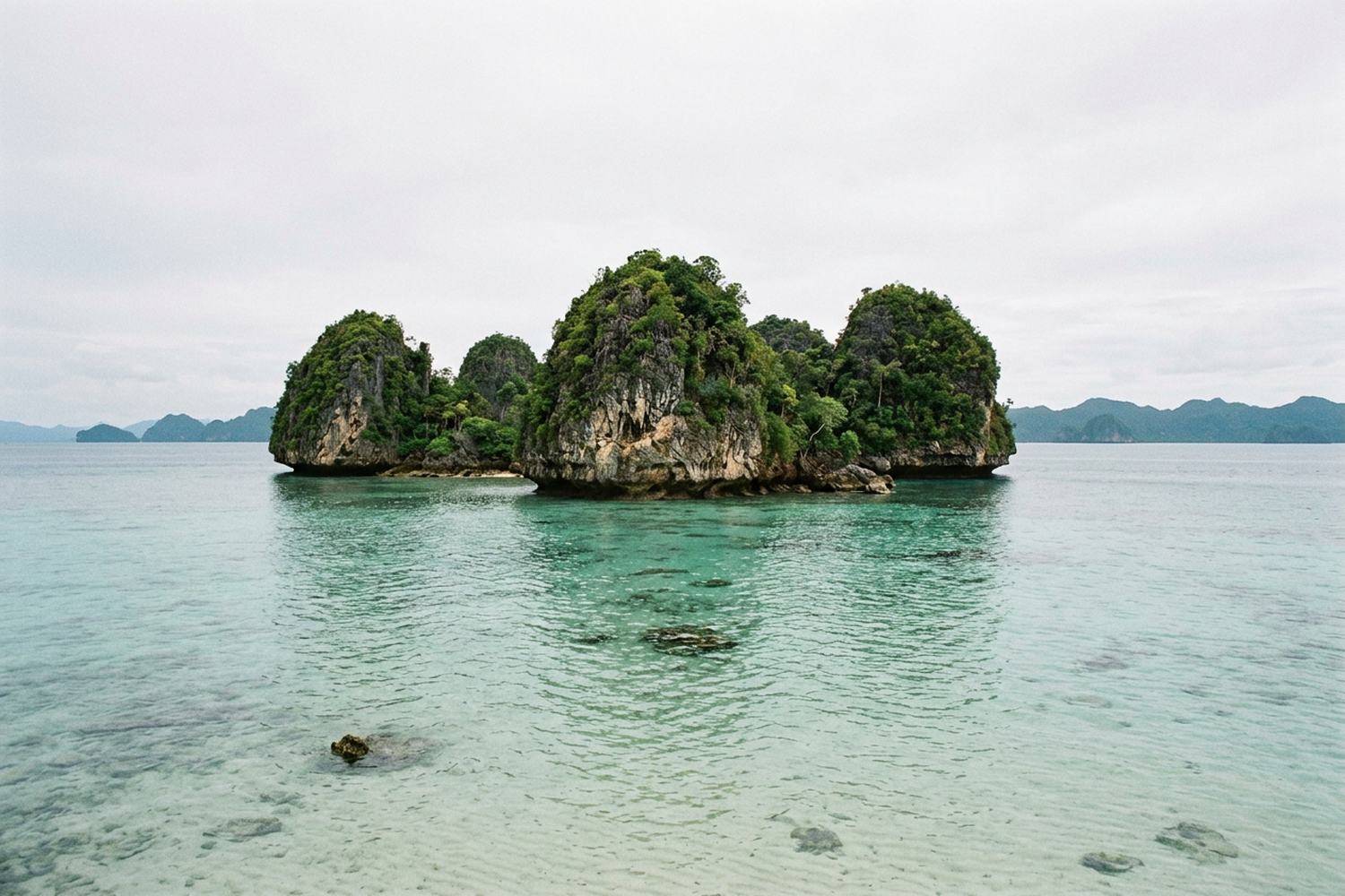Dome shaped limestone islets covered in green rising out of clear turquoise shallows.